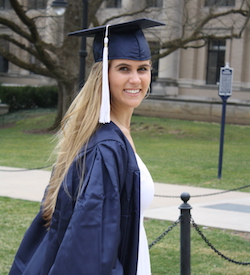 Julia Minakowski in her graduation gown outside on campus.